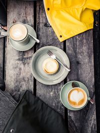 High angle view of coffee cups with cookies served on wooden table