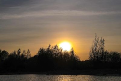 Silhouette trees by lake against sky during sunset