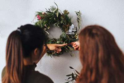 Midsection of woman holding flowering plants against wall