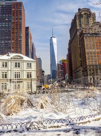 Snow covered buildings in city against sky