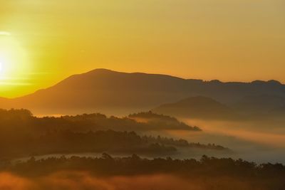 Scenic view of silhouette mountains against orange sky