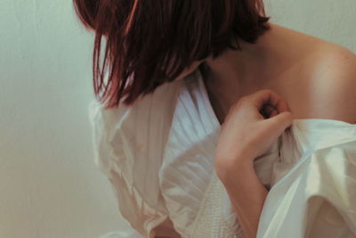 Close-up of bride wearing wedding dress against wall