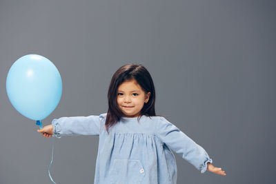 Portrait of young woman with balloons against clear sky