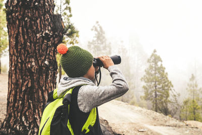 Boy looking through binoculars at forest
