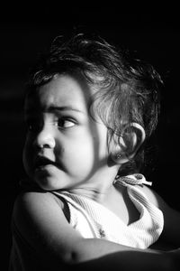 Portrait of cute girl looking away against black background