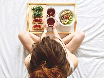 Directly above shot of woman having breakfast on bed