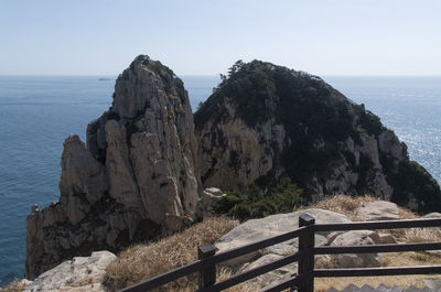 Scenic view of sea by mountains against clear sky