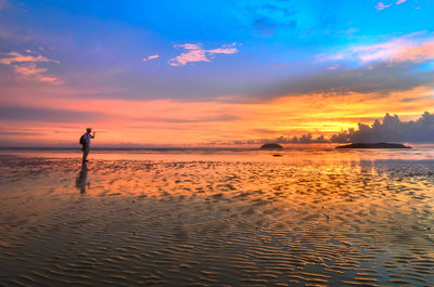 Silhouette man standing on beach against sky during sunset