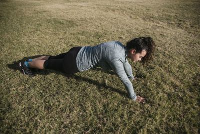 Woman doing push ups on the grass.