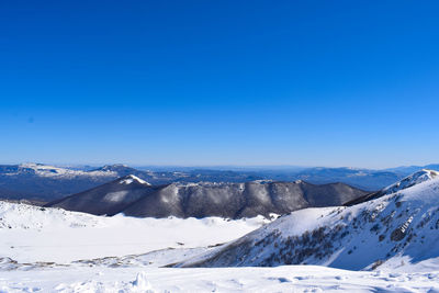 Scenic view of snowcapped mountains against clear blue sky