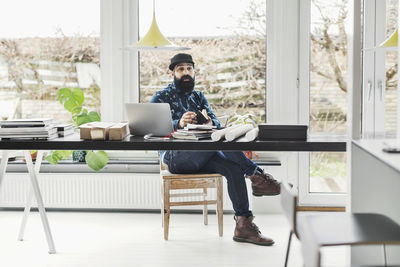 Male architect sitting at table by window