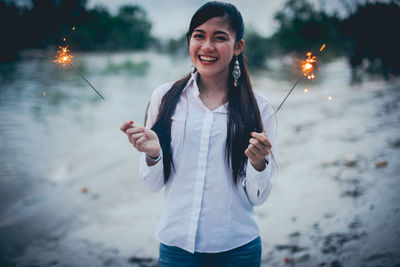 Portrait of smiling young woman standing at park