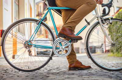 Young stylish businessman go to work on his sport retro bike in sunny day on city street