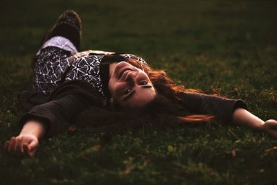 Portrait of beautiful woman lying on grass at park during sunset