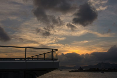 Silhouette bridge over sea against sky during sunset