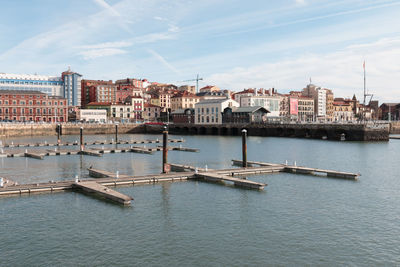 Scenic view of river by buildings against sky