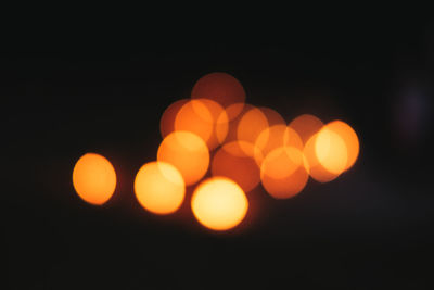 Defocused image of illuminated lights against sky at night