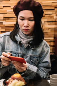 Woman using phone while having food at table in restaurant