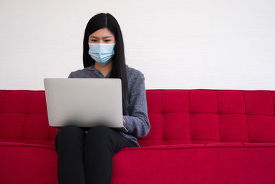 Young woman using laptop sitting on sofa at home