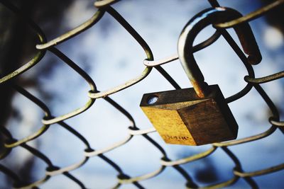 Close-up of love lock on fence against sky