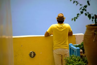 Rear view of man standing against yellow sky