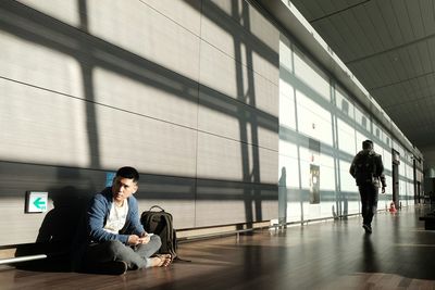 Mid adult man sitting on walkway at airport