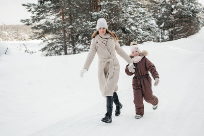 Mother and daughter have fun running in the snowy forest. high quality photo