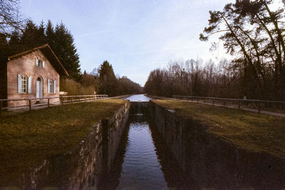 Canal amidst trees and buildings against sky