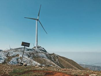 Wind turbines on landscape against clear blue sky