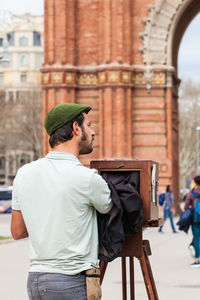 Young man wearing hat standing against city in background