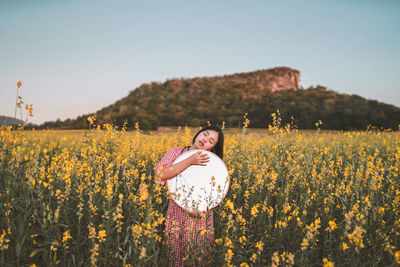 Portrait of woman standing on field against clear sky