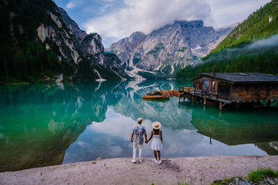 People standing by lake against mountains