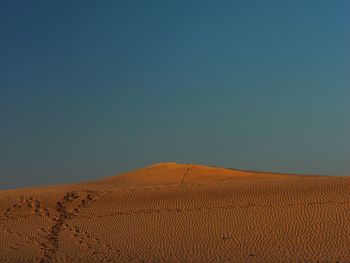 Scenic view of desert against clear blue sky