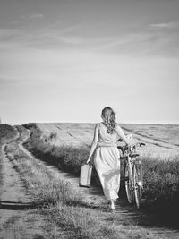 Full length of woman with bicycle walking on field