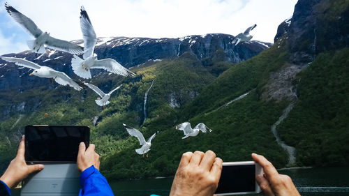 Cropped hands of men using mobile phone on mountain