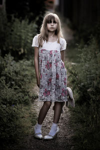 Portrait of girl holding stuffed toy and standing on field