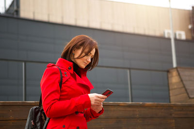 Young woman using mobile phone while standing at camera