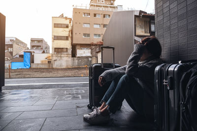 Rear view of man sitting on street against buildings