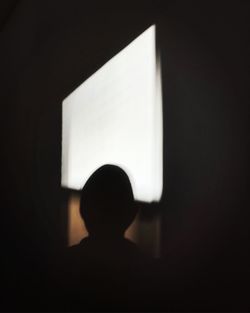 Rear view of silhouette boy against black background