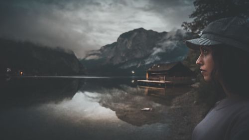 Side view of woman looking at lake against mountains