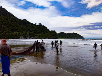 People at beach against sky