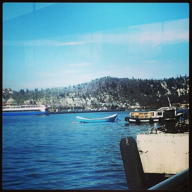 water, transfer print, nautical vessel, moored, boat, auto post production filter, transportation, mode of transport, sky, sea, blue, building exterior, harbor, nature, built structure, tranquility, day, tranquil scene, lake, architecture