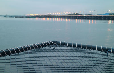 Closeup empty over-water hammock bed with blurry sea bridge in the backdrop