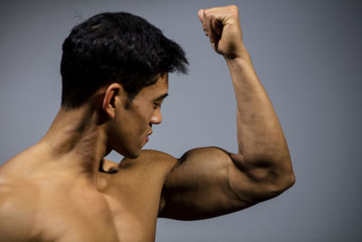 Shirtless muscular man standing against wall