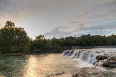 Scenic view of waterfall against sky during sunset