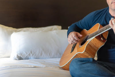 Midsection of man playing guitar