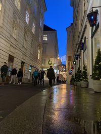 People walking on illuminated street amidst buildings in city at night