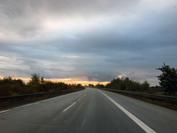 Empty country road against cloudy sky