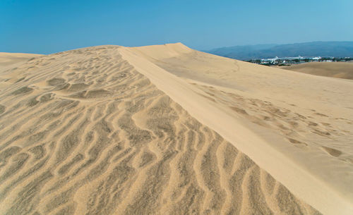 Sand dunes in desert against clear sky