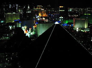 Illuminated street amidst buildings in city at night